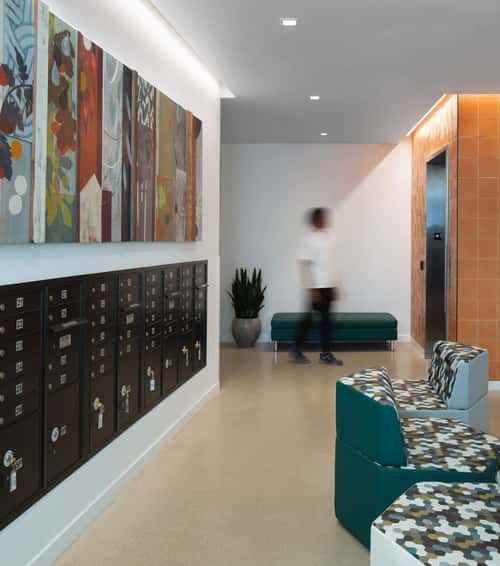 Flanged square LED recessed lights with white trim light a path from apartment mailboxes to an elevator in the Wilton Court Apartments lobby.
